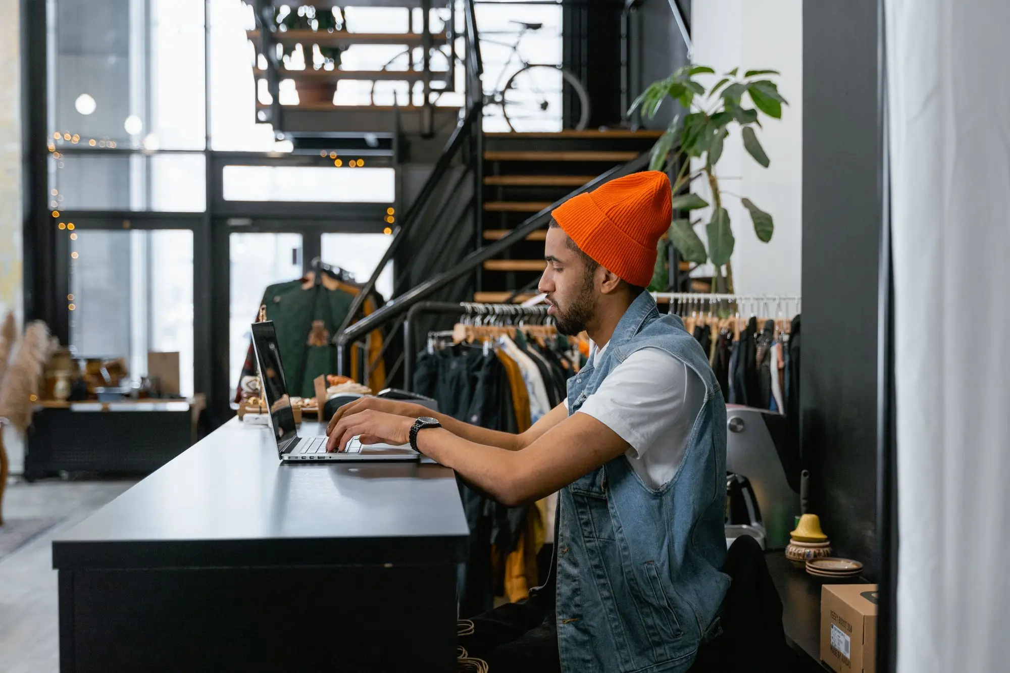 Clothing store owner working on a laptop at the shop counter, planning a new website and online store